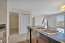 Kitchen featuring a double basin sink with a chrome faucet, dark countertops, and dark wood cabinetry - 415 12035 22 Avenue, Edmonton, AB  - Indoor Photo Showing Kitchen With Double Sink 