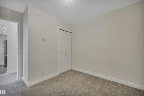 This room features light-colored walls and grey carpet flooring - 415 12035 22 Avenue, Edmonton, AB - Indoor Photo Showing Other Room