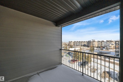 The property features a private balcony with a black metal railing, offering expansive views of the surrounding community, which includes other residential buildings and a street - 415 12035 22 Avenue, Edmonton, AB - Outdoor With Balcony With Exterior