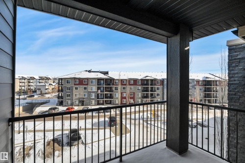 The property features a private balcony with a black metal railing, offering a clear view of the surrounding residential buildings and snow-covered terrain - 415 12035 22 Avenue, Edmonton, AB - Outdoor With Balcony With Exterior