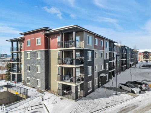 The property features an exterior with a mix of brick and siding, balconies with black railings, and several windows - 415 12035 22 Avenue, Edmonton, AB - Outdoor With Balcony