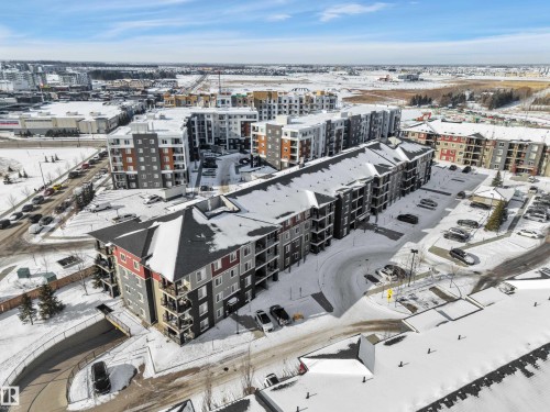 Aerial view highlighting the property's exterior, including a paved parking lot and a surrounding area with other residential buildings - 415 12035 22 Avenue, Edmonton, AB - Outdoor With View