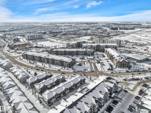 Aerial view showcasing a community with townhomes and apartment buildings, surrounded by a winter landscape - 415 12035 22 Avenue, Edmonton, AB - Outdoor With View
