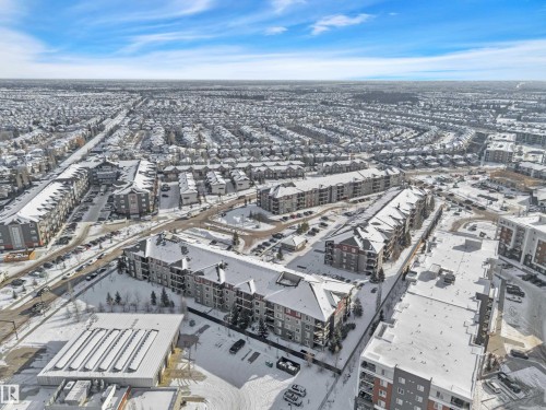 Aerial view of the community, showcasing residential buildings and roads covered in snow under a clear blue sky - 415 12035 22 Avenue, Edmonton, AB - Outdoor With View
