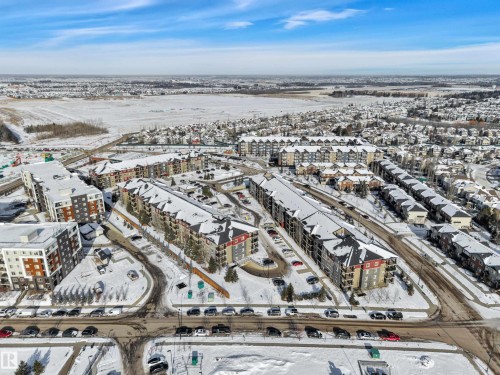 The property is situated within a development featuring multi-story buildings and townhouses, all with snow-covered roofs - 415 12035 22 Avenue, Edmonton, AB - Outdoor With View