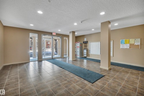 The property features an entrance area with tiled flooring, recessed lighting, and glass doors - 415 12035 22 Avenue, Edmonton, AB - Indoor Photo Showing Other Room