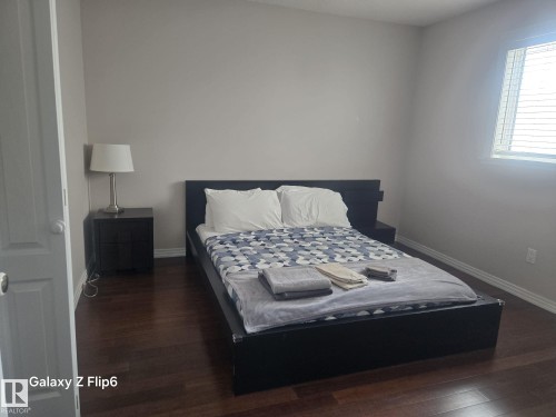 This room features dark wood flooring, light-colored walls, and a window with blinds - Edmonton, AB - Indoor Photo Showing Bedroom