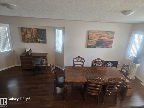 The property features dark hardwood flooring throughout this area, illuminated by natural light from windows with horizontal blinds - Edmonton, AB - Indoor Photo Showing Dining Room