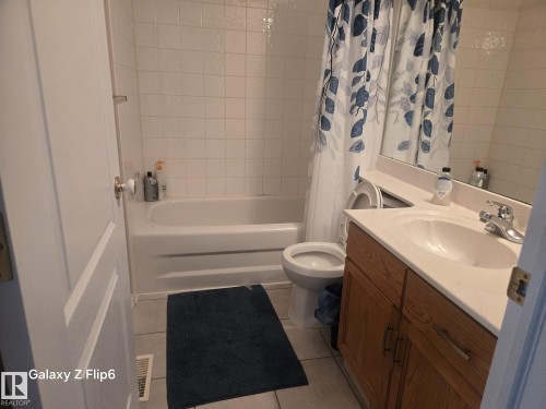 Bathroom with a vanity featuring a built-in sink, a bathtub with white tiled walls, and a toilet - Edmonton, AB - Indoor Photo Showing Bathroom