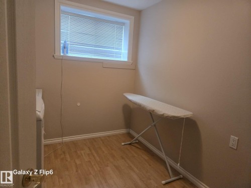 The property features a dedicated space with wood-look flooring and a window with blinds - Edmonton, AB - Indoor Photo Showing Other Room