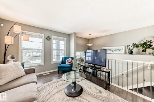 Living area featuring large windows, hardwood floors, and a railing overlooking a staircase - 86 4029 Orchards Drive, Edmonton, AB - Indoor Photo Showing Living Room