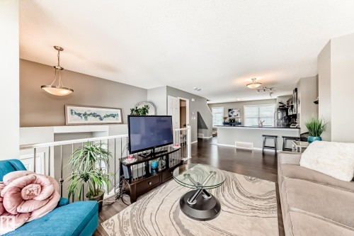 This property features an open-concept living area with dark hardwood flooring and light-colored walls - 86 4029 Orchards Drive, Edmonton, AB - Indoor Photo Showing Living Room