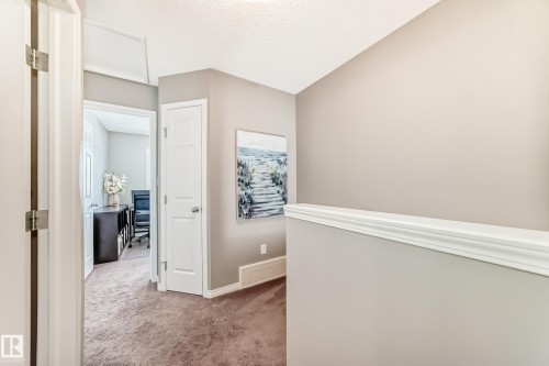 The property features neutral toned walls, carpeted flooring, and white trim throughout the hallway - 86 4029 Orchards Drive, Edmonton, AB - Indoor Photo Showing Other Room