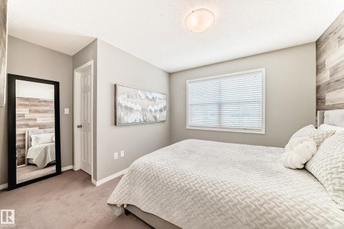The room features light gray walls, a window with blinds, and a textured accent wall - 86 4029 Orchards Drive, Edmonton, AB - Indoor Photo Showing Bedroom