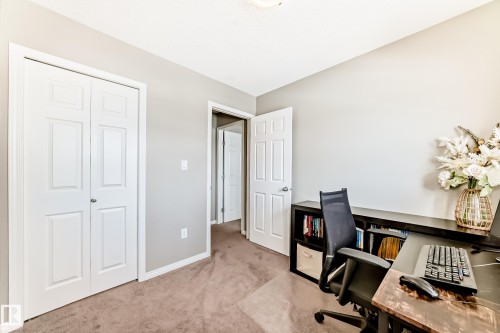 This versatile room features neutral-toned carpeting and walls, along with a built-in shelving unit - 86 4029 Orchards Drive, Edmonton, AB - Indoor Photo Showing Office