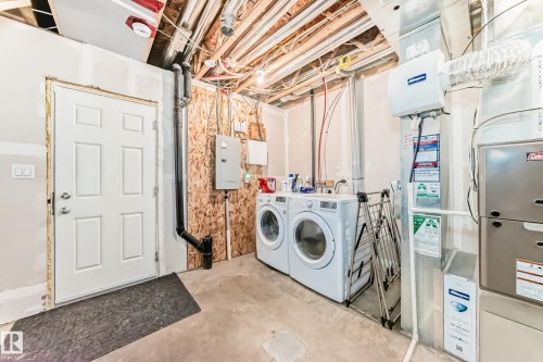 The utility area features a white paneled door, exposed ceiling joists, and a concrete floor - 86 4029 Orchards Drive, Edmonton, AB - Indoor Photo Showing Laundry Room