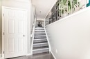 Entryway featuring a white paneled door, tiled flooring, and a staircase with a white railing - 86 4029 Orchards Drive, Edmonton, AB  - Indoor Photo Showing Other Room 
