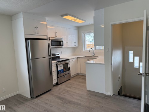The kitchen features white cabinetry, stainless steel appliances, and light-colored quartz countertops - 13323 68 Street, Edmonton, AB - Indoor Photo Showing Kitchen With Upgraded Kitchen