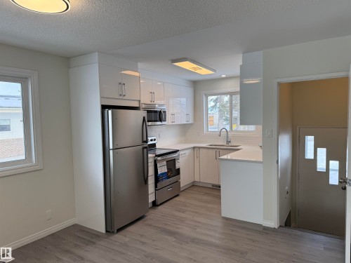 Bright kitchen featuring white cabinetry, stainless steel appliances, a white tile backsplash, and light-colored quartz countertops - 13323 68 Street, Edmonton, AB - Indoor Photo Showing Kitchen