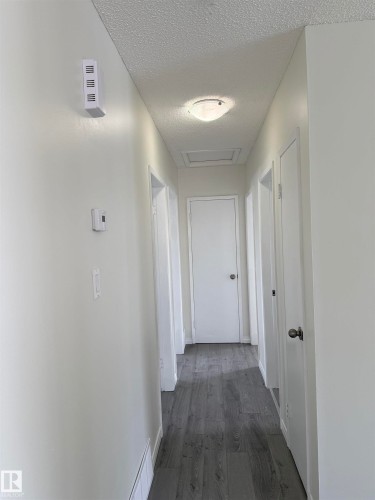 Hallway featuring light gray luxury vinyl plank flooring, white walls, and a ceiling-mounted light fixture - 13323 68 Street, Edmonton, AB - Indoor Photo Showing Other Room