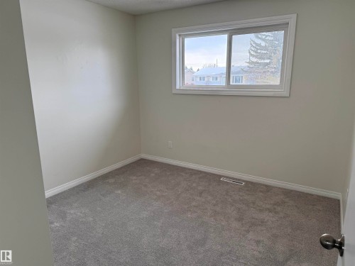 This room features light-colored walls, gray carpet, and a white-framed window - 13323 68 Street, Edmonton, AB - Indoor Photo Showing Other Room