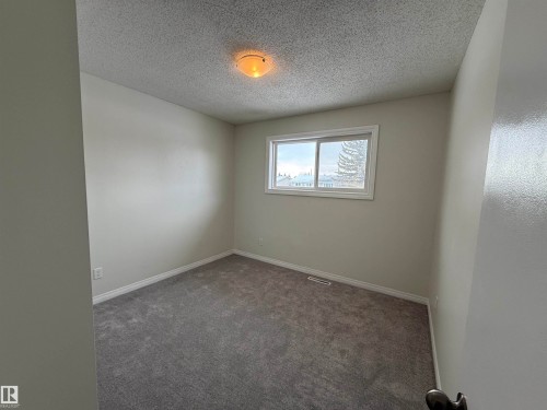 The room features neutral-toned walls, a window providing natural light, and grey carpeting - 13323 68 Street, Edmonton, AB - Indoor Photo Showing Other Room