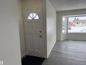 Entryway with a white paneled door featuring a decorative fanlight, leading into a room with grey luxury vinyl planks - 13323 68 Street, Edmonton, AB  - Indoor Photo Showing Other Room 