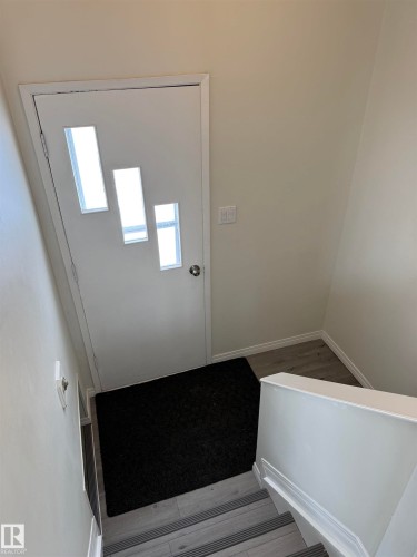 Entryway with a white door featuring three rectangular window panels, light-colored walls, and a light switch on the wall - 13323 68 Street, Edmonton, AB - Indoor Photo Showing Other Room