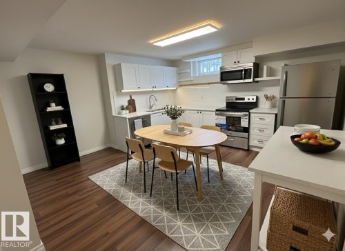 The property features hard flooring throughout the main area, a kitchen with white cabinetry, stainless steel appliances, and a rectangular light fixture - 13323 68 Street, Edmonton, AB - Indoor