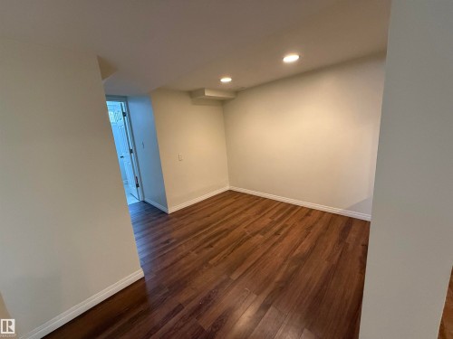 This space features recessed lighting and durable wood-style flooring, complemented by light-colored walls and white baseboards - 13323 68 Street, Edmonton, AB - Indoor