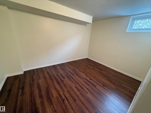 The room features rich brown flooring, light-colored walls, and a window. - 13323 68 Street, Edmonton, AB - Indoor Photo Showing Other Room