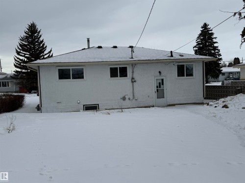 The property features a white stucco exterior, multiple windows, and a rear entrance door - 13323 68 Street, Edmonton, AB - Outdoor