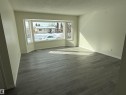 This room features a large bay window, light-colored walls, and luxury vinyl plank flooring - 13323 68 Street, Edmonton, AB  - Indoor Photo Showing Other Room 