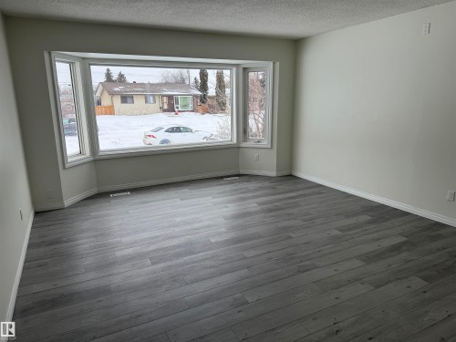 This room features expansive bay windows, white trim, and light-colored walls - 13323 68 Street, Edmonton, AB - Indoor Photo Showing Other Room