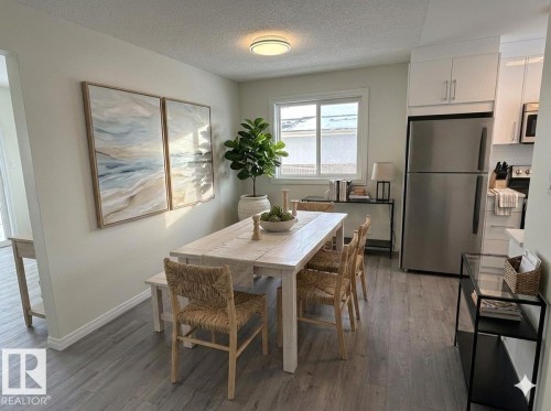 Dining area featuring luxury vinyl plank flooring, a window providing natural light, and an open layout with the kitchen - 13323 68 Street, Edmonton, AB - Indoor