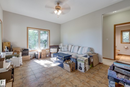 Living area featuring tiled flooring, a window with wood trim, and a ceiling fan - 602 Pheasant Close, Rural Camrose County, AB - Indoor Photo Showing Other Room