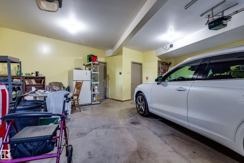 The property includes a spacious garage with a concrete floor, overhead lighting, and an automatic garage door opener - 602 Pheasant Close, Rural Camrose County, AB - Indoor Photo Showing Garage