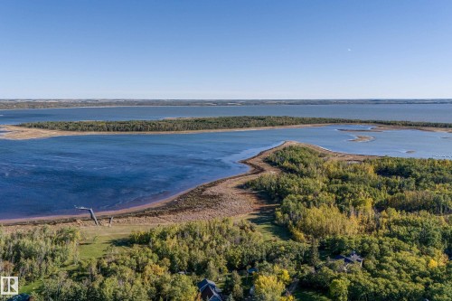 This property offers a vast expanse of verdant land, partially wooded, with a shoreline bordering a large body of water - 602 Pheasant Close, Rural Camrose County, AB - Outdoor With Body Of Water With View