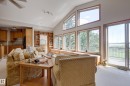 The open-concept living area features a vaulted ceiling, extensive built-in shelving, and large windows with views of the surrounding trees and water - 602 Pheasant Close, Rural Camrose County, AB  - Indoor 