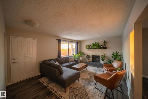Living area with a fireplace, dark wood-style floors, and a textured ceiling - 2311 146 Avenue, Edmonton, AB - Indoor Photo Showing Living Room With Fireplace