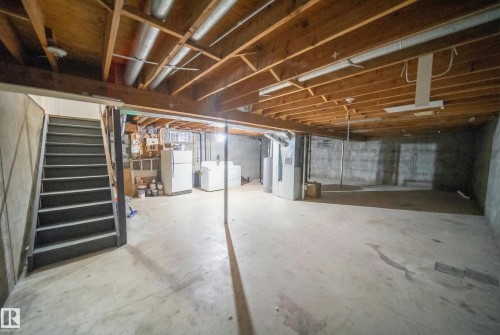 Unfinished below grade area featuring freestanding refrigerator, stairs, heating unit, washing machine and clothes dryer, and water heater - 2311 146 Avenue, Edmonton, AB - Indoor Photo Showing Basement