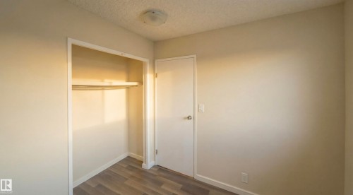 Unfurnished bedroom featuring a textured ceiling, dark wood-style floors, and a closet - 2311 146 Avenue, Edmonton, AB - Indoor Photo Showing Other Room