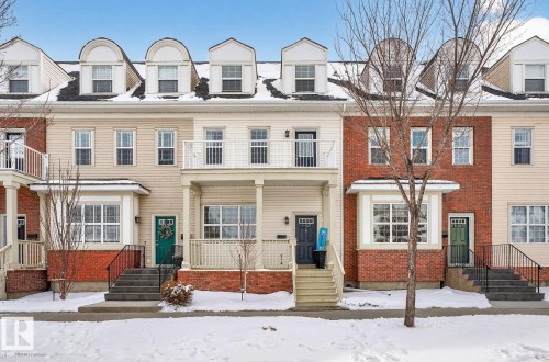 The property features a charming covered porch with columns, a private balcony, and a bay window - 11 4367 Veterans Way, Edmonton, AB - Outdoor With Facade