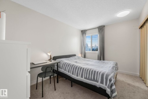 This room features a window with curtains, carpeted flooring, and a ceiling-mounted light fixture - 33 4403 Riverbend Road, Edmonton, AB - Indoor Photo Showing Bedroom