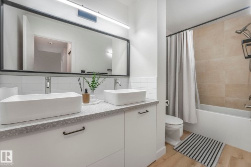 Bathroom featuring a double vanity with rectangular vessel sinks, a wide mirror, and a bathtub with a shower - 33 4403 Riverbend Road, Edmonton, AB - Indoor Photo Showing Bathroom