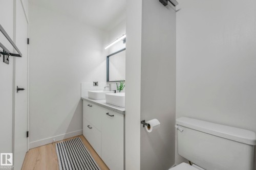 Bathroom featuring a dual vanity with white vessel sinks, light-colored countertops, and modern black hardware - 33 4403 Riverbend Road, Edmonton, AB - Indoor Photo Showing Bathroom