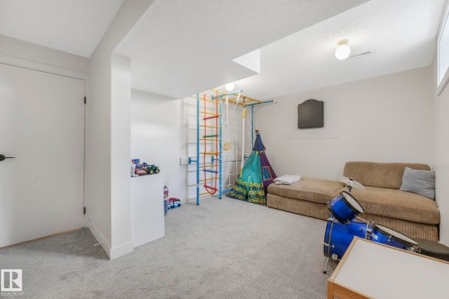 This spacious room features light gray carpet flooring and white walls, creating a bright and neutral aesthetic - 33 4403 Riverbend Road, Edmonton, AB - Indoor