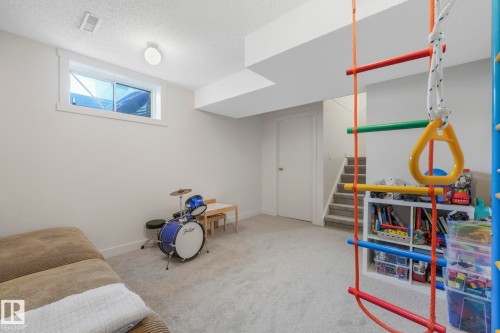 Spacious recreation room featuring light grey carpeting, white walls, and a window providing natural light - 33 4403 Riverbend Road, Edmonton, AB - Indoor