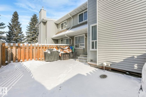 The property exterior features horizontal siding, a private fenced yard, and an external staircase leading to an entrance - 33 4403 Riverbend Road, Edmonton, AB - Outdoor