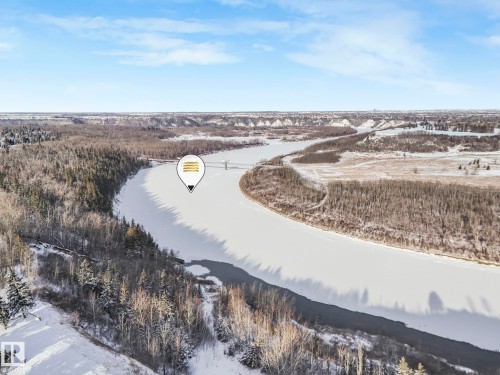 Aerial view of the surrounding landscape, featuring a winding river with sections of ice and open water, bordered by snow-covered terrain and extensive tree coverage - 33 4403 Riverbend Road, Edmonton, AB - Outdoor With View